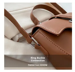 Detail of silver ring buckle and stitching on brown leather crossbody bag