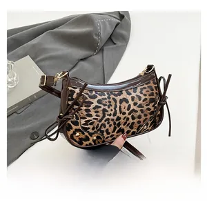 Detail of leopard print underarm bag featuring patent leather trim and side bow accents