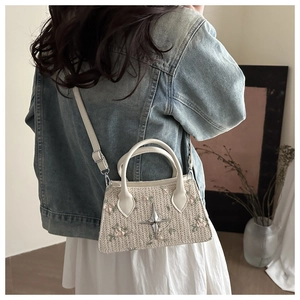 Detail of floral embroidery and star metal stud on a straw woven crossbody bag