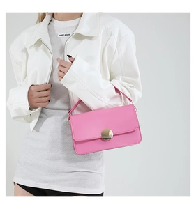 Détail du sac à rabat rose avec une grande boucle circulaire en métal doré élégante
