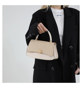 Close-up of contrast texture baguette bag with woven flap and smooth cream leather