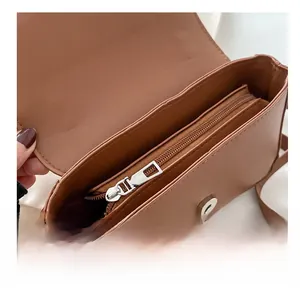Detailed view of the smooth silver zipper and interior compartment of the brown square bag