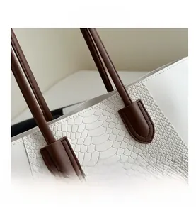 Detail showing high-quality white faux leather with crocodile texture and brown handle stitching