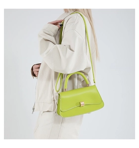 Model wearing bright green leather small square crossbody bag with gold buckle detail