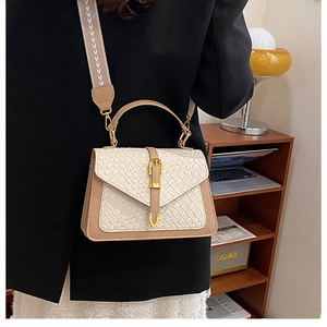 Detail of contrast color crossbody bag with woven texture lid and wide patterned strap