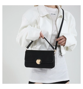 Détail d'un sac à main noir en cuir avec un grand fermoir rond en métal doré élégant
