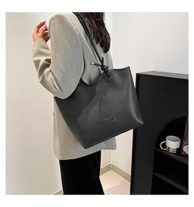 Side view of model wearing a black leather tote bag with knotted handle detail