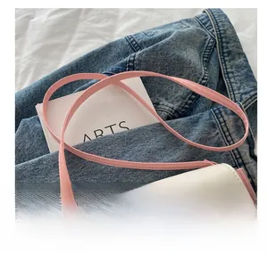 Detail of pink and white crossbody bag with cartoon print on denim jacket background