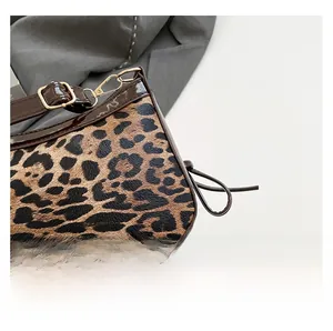 Close-up of leopard print faux fur texture with dark brown patent leather trim and gold hardware