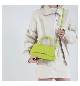 Vista a tracolla di una borsa minimalista verde lime in pelle con fibbia oro chiaro