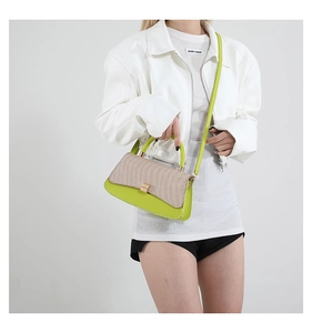 Close-up of green leather and beige woven fabric detail on a stylish baguette bag