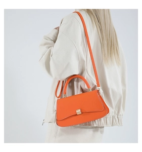 Borsa a tracolla arancione vivace con fibbia dorata su modella in stile minimalista