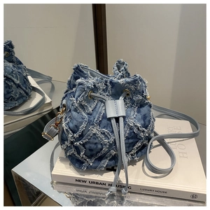 Dettaglio borsa a secchiello in denim trapuntato con coulisse in pelle blu e finiture oro