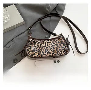 Close-up of leopard print crescent bag with brown patent leather trim and size comparison