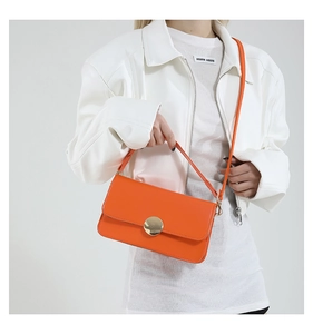 Détail du sac à bandoulière en cuir orange vif avec une grande boucle ronde dorée polie
