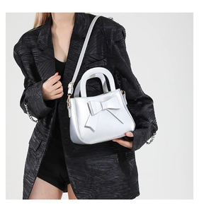 Borsa a mano argento con fiocco su blazer nero indossata da una modella in studio