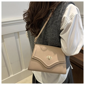 Detailed view of beige faux leather shoulder bag with gold oval twist lock on a model