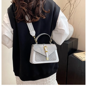 Detail of silver woven crossbody bag with gold lock and wide geometric shoulder strap