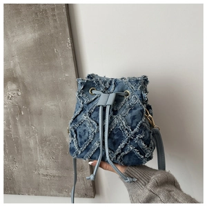 Dettaglio della borsa a secchiello in denim trapuntato con bordi sfrangiati e coulisse