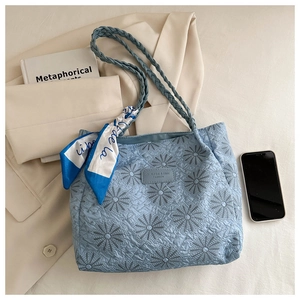 Close-up of light blue tote bag featuring floral daisy embroidery and a decorative silk scarf
