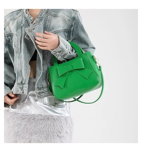 Dettaglio borsa in pelle verde lime con grande fiocco e tracolla in oro metallo