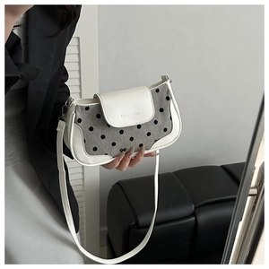 Detailed view of polka dot underarm bag with white leather trim and bow detail