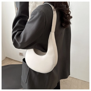 Minimalist white crescent shoulder bag shown on model wearing grey oversized blazer