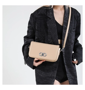 Detail of light beige leather crossbody bag with silver oval metal buckle on black suit