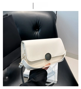 Détail d'un sac bandoulière blanc brillant avec fermoir magnétique rond en métal