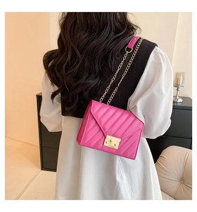 Hot pink quilted chain bag with V-shaped stitching and gold clasp in a lifestyle setting