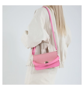 Detail view of pink textured fabric flap and round metal lock on stylish shoulder bag