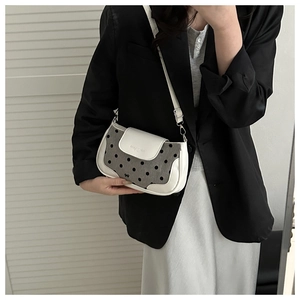 Détail du sac à rabat en cuir blanc à pois noirs et petit nœud métallique chic