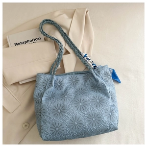 Detail of light blue tote bag featuring daisy embroidery and textured pleated fabric