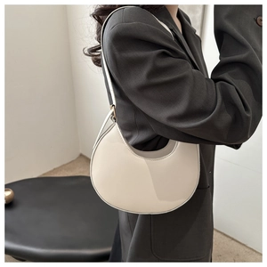 Side view of white crescent moon underarm bag on a model in a dark gray blazer