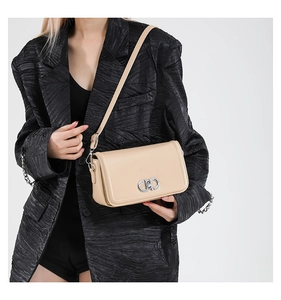 Detail of beige rectangular leather shoulder bag with silver interlocking metal buckle