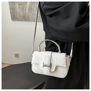Detail of white leather crossbody bag with silver buckle and sleek shoulder strap