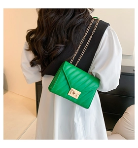 Detail der grünen Stepptasche mit goldener Kette und elegantem Drehverschluss für Damen