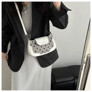 Détail du sac en cuir blanc et toile grise à pois avec décoration de nœud élégante