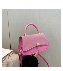 Detailed close-up of pink leather small square bag with golden lock and stripe texture
