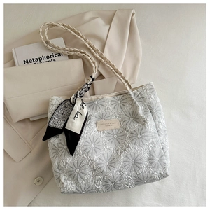 Detail of floral embroidery on cream tote bag with twisted handle and silk scarf