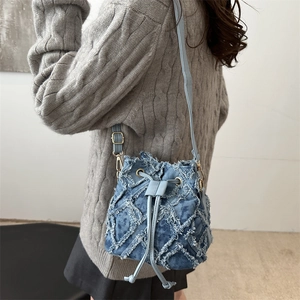 Borsa a secchiello in denim trapuntato azzurro con texture sfrangiata e coulisse