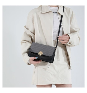 Detail of grey fabric and black leather contrast crossbody bag with gold metal buckle