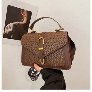 Detail of retro woven handbag with golden U-buckle and geometric patterned strap