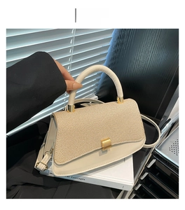 Detail of khaki straw texture and creamy leather on saddle bag with golden hardware
