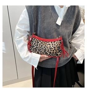 Detail of red bow accents and leopard print texture on a retro underarm bag