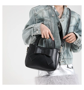 Detail of elegant black crossbody bag with large bow and premium matte leather texture