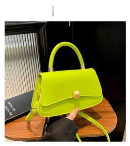 Close-up of green leather handbag with gold metal clasp and detachable strap detail