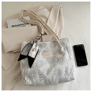 Detail view of white tote bag featuring daisy floral embroidery and decorative silk scarf