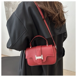 Model wearing a red leather crossbody bag with silver H-buckle and black coat