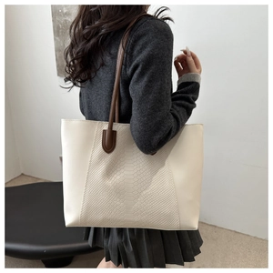Detail of off-white tote bag with embossed crocodile pattern and brown shoulder straps